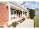 Inviting front porch with white columns, rocking chairs, and beautifully landscaped garden beds at 237 Summerford Pl, Stockbridge, GA 30281