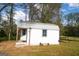 White outbuilding with gray trim, covered porch, and decorations in a grassy yard surrounded by trees at 237 Summerford Pl, Stockbridge, GA 30281