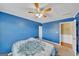 Bright bedroom featuring blue walls, ceiling fan, and doorway to adjacent room at 720 Strawflower Ln, Locust Grove, GA 30248