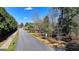 Neighborhood street view lined with mature trees and single-Gathering homes under a clear blue sky at 768 Scales Rd, Suwanee, GA 30024