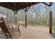 Covered brick patio featuring wooden posts and rocking chairs overlooking the backyard at 308 Tussahaw Trl, Locust Grove, GA 30248