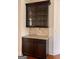 Elegant bar area featuring upper cabinets with glass fronts and stone backsplash at 3393 Willow Glen Trl, Suwanee, GA 30024