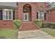 Close-up of the brick home's arched front entrance with decorative shrubbery and white trimmed windows at 3530 Highway 81 W, Hampton, GA 30228