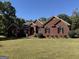 Charming red brick home featuring a lush green lawn and mature trees under a clear blue sky at 3530 Highway 81 W, Hampton, GA 30228