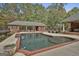A backyard in-ground pool with waterfall feature, pool house, and lush greenery at 3530 Highway 81 W, Hampton, GA 30228