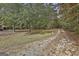 Driveway approaching a wooded lot with fall foliage with a home in the distance at 3530 Highway 81 W, Hampton, GA 30228