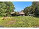 Large backyard with a lush lawn, mature trees, and a view of the home's exterior, perfect for outdoor activities at 135 Horseshoe Cir, Fayetteville, GA 30215