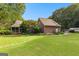 Sprawling backyard featuring a lush green lawn, mature trees, stone pathway, and an outbuilding at 135 Horseshoe Cir, Fayetteville, GA 30215