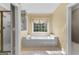 Bathroom features a large tub and glass enclosed shower next to a window at 135 Horseshoe Cir, Fayetteville, GA 30215