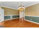 Elegant dining room featuring hardwood floors, wainscoting, and a stunning gold chandelier at 135 Horseshoe Cir, Fayetteville, GA 30215