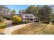 Charming home featuring a welcoming front porch, brick chimney, mature trees, and lush green lawn at 135 Horseshoe Cir, Fayetteville, GA 30215