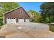 Spacious three-car garage on a charming home with a brick chimney surrounded by lush greenery and a long driveway at 135 Horseshoe Cir, Fayetteville, GA 30215