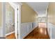 Hallway featuring wainscoting, hardwood floors, and access to a powder room at 135 Horseshoe Cir, Fayetteville, GA 30215