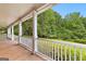 Inviting porch with white railings and columns, offering serene views of the lush green lawn and mature trees at 135 Horseshoe Cir, Fayetteville, GA 30215