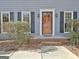 Close-up of the front door with decorative wreath, flanked by windows with black shutters and brick steps at 233 Creekstone Bnd, Peachtree City, GA 30269