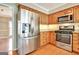 Updated kitchen with stainless steel fridge, gas range, granite counters, and ample wooden cabinet storage space at 233 Creekstone Bnd, Peachtree City, GA 30269