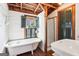 Rustic bathroom featuring white walls, a clawfoot tub, rustic wood beams, and green shutters at 1009 Institute Nw St, Conyers, GA 30012