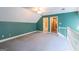 A bonus room with green walls features a doorway, white railing, and a neutral color carpet at 115 Flagstop Run, Fayetteville, GA 30215