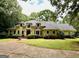 Traditional home featuring a lush lawn, mature trees, and a circular driveway with a decorative fountain at 115 Flagstop Run, Fayetteville, GA 30215