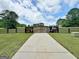 Long driveway leads to the electric entry gate with manicured lawn and mature trees at 129 Old Norton Rd, Fayetteville, GA 30215