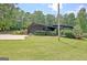 View of the home's exterior with dark gray siding, lush landscaping and large front yard at 129 Old Norton Rd, Fayetteville, GA 30215