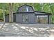 Modern barn-style home with black exterior, concrete patio, and surrounded by mature trees at 129 Old Norton Rd, Fayetteville, GA 30215