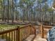 Wooden deck with railing overlooks a lush, wooded backyard, featuring a grill and woodpile at 115 Christie Ln, Mcdonough, GA 30252