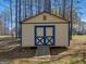A charming outbuilding or shed with a blue door sits nestled among mature trees at 115 Christie Ln, Mcdonough, GA 30252