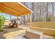 Entertainer's covered deck with outdoor dining area, grill and built-in bench, surrounded by a lush landscape at 104 Pine Pt, Peachtree City, GA 30269