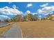 Picturesque view of a pond with lush grass, trees, and a paved path under a partly cloudy sky at 265 High St, Fayetteville, GA 30214