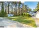 Backyard with a shed, a patio area and green grass with scattered flowers underneath mature trees at 3685 Concordia Rd, Decatur, GA 30034