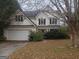 Two-story home featuring white siding, a two-car garage, and a front yard landscaped with bushes and mature trees at 50 Village Walk, Covington, GA 30016
