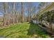 A landscaped backyard with lush lawn, tall trees, and a charming porch visible from the side of the house at 65 Dundee Pl, Sharpsburg, GA 30277