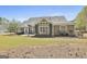 The house back exterior features manicured lawn, gray siding, white trim, and a beautifully landscaped perimeter at 410 Denton Cir, Fayetteville, GA 30215