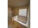 Bright bathroom featuring a soaking tub and tiled walk-in shower with window view at 2470 Wevok Way, Grayson, GA 30017