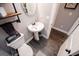 Cozy half-bathroom featuring a pedestal sink, dark wood-look tile flooring, and modern fixtures at 640 Lovell Rd, Temple, GA 30179