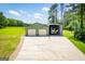 Green garage with two doors and an open carport, complemented by a large concrete driveway and landscaping at 640 Lovell Rd, Temple, GA 30179