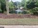 Scenic view of a pond with fountain surrounded by mulch, grass, and trees at 227 Fenwick Cir, Mcdonough, GA 30253