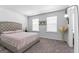 Bedroom with a tufted headboard bed, neutral walls, two windows, and carpet flooring at 813 Royal Red Ct, Mcdonough, GA 30253