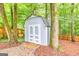 Backyard shot of a light blue shed with double doors nestled in the trees behind a wood fence at 346 Buckingham Sw Dr, Conyers, GA 30094