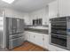 Modern kitchen showcasing stainless steel appliances, granite countertops, and white cabinetry with beautiful hardwood floors at 200 Magnolia Ct, Mcdonough, GA 30252