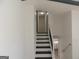 Staircase with neutral carpeting, white walls, a black handrail, and a landing at 851 Bridgewater Ct, Stone Mountain, GA 30088