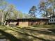 Lush backyard showcasing the home's brick exterior, surrounded by mature trees and ample green space at 4063 Windsor Castle Way, Decatur, GA 30034