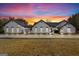 Stunning white brick home with black roof, green lawn, and picturesque sunset sky at 2615 Hampton Locust Grove Rd, Locust Grove, GA 30248