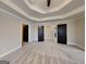 Spacious main bedroom with tray ceiling, carpet, and multiple doors leading to ensuite bathroom at 483 Castle Top Ln, Lawrenceville, GA 30045
