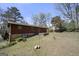 Exterior view of home's back and yard with mature trees and a small patio area; some equipment in view at 5217 Hollyhock Rd, Douglasville, GA 30135
