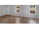 Bright empty room with wood flooring, two windows, a white door and neutral walls at 1293 Coan Dr, Locust Grove, GA 30248