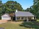 Charming single-story home featuring manicured landscaping, a covered porch, and a detached two-car garage at 1293 Coan Dr, Locust Grove, GA 30248