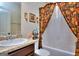 Well-lit bathroom featuring a sink, toilet, and shower with floral curtains at 1058 Hartwell Rd, Locust Grove, GA 30248