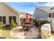 Landscaped backyard featuring a custom stone patio with a red umbrella and outdoor furniture at 365 Grand Teton Cir, Fayetteville, GA 30215